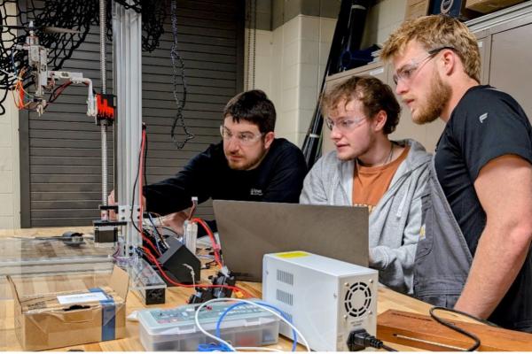 Sophomore undergraduate students Gable Rath and Cade Spurlock explain to Dr. Roghanchi how they used AI to help solve a sensor problem while designing an autonomous drone.